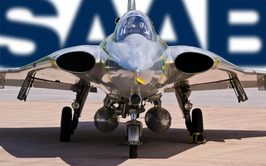 Saabs stridsflygplan Gripen fotograferat framifrån på landningsbanan, med Saabs logotyp i bakgrunden, symbol för försvars- och flygindustrin kopplat till saab aktie.