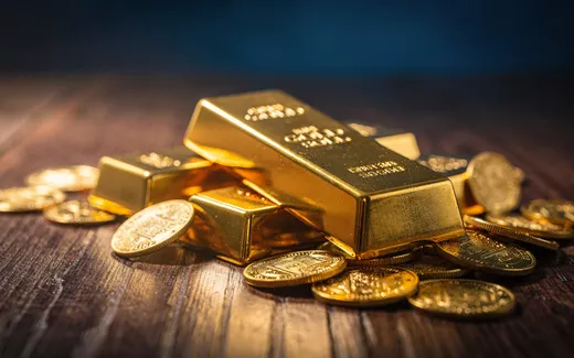 Guldtackor och mynt på mörk träyta med varmt ljus