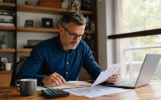 Person som arbetar med privatekonomi vid skrivbord hemma