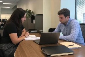 Två personer granskar dokument tillsammans vid ett arbetsbord på ett certifieringsorgan.